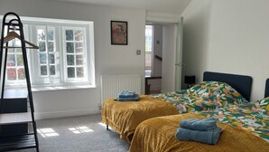 A bedroom with two beds, a radiator, a window, and a door leading to another room. - Charming pottery barn conversion 2 mins from Horsforth train station. (Horsforth)