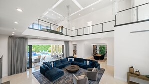 Ein geräumiger Wohnbereich mit Ecksofa, Couchtisch und Blick auf einen Pool.