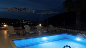 A swimming pool with tiled edges, surrounded by lounge chairs and umbrellas, and a stone wall in the background. - Villa Sol - 3-bedroom villa in amazing Bali with private pool, AC, WiFi (Mpali)