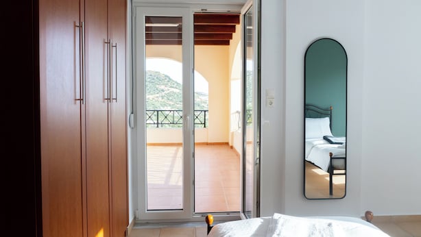 A bedroom with a bed, a sliding glass door leading to a balcony, and a large mirror on the wall. - Villa Sol - 3-bedroom villa in amazing Bali with private pool, AC, WiFi (Mpali)