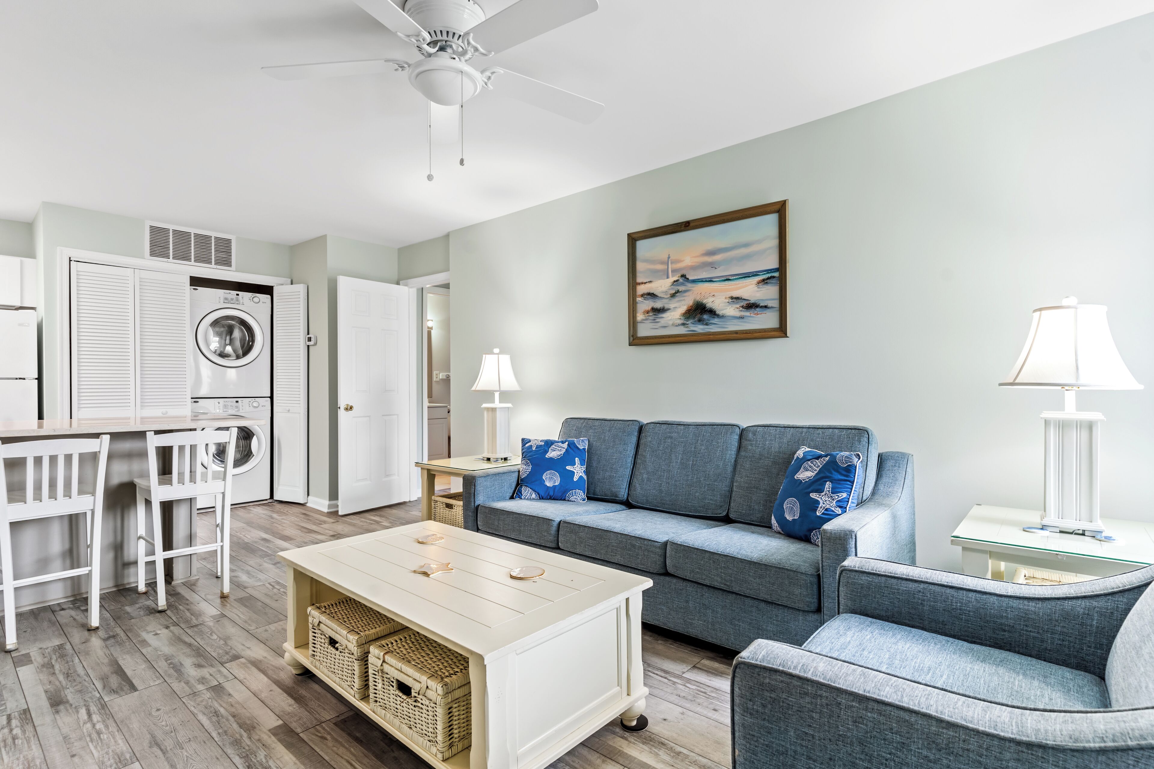 A modern living room with a grey sofa, a wooden coffee table, and a ceiling fan.