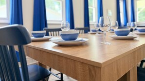 A dining area with blue curtains, a wooden table, and matching blue and white plates and bowls.