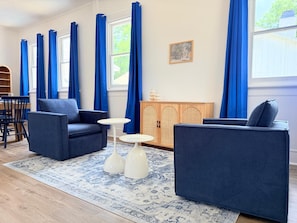 Una sala de estar con dos sofás azul oscuro, una mesita blanca y una alfombra estampada.