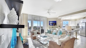 A spacious living room with a large window, a dining area, and a kitchen. - Regatta - WALK TO THE BEACH (Naples)