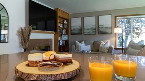 Un comedor con una mesa de madera que presenta postres y dos vasos de zumo de naranja.