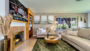 Una sala de estar con chimenea, sofá, mesa de centro y estantería.