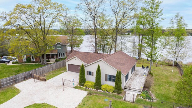 A two-story house with a fenced backyard, a covered patio, and a view of a lake. - Cozy Lakefront Home, Minutes from Lake MI, 2 Bedrooms, 2 Bathrooms. Sleeps 6 (Manistee)