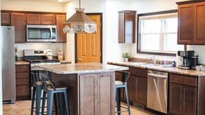 A modern kitchen with a central island, stainless steel appliances, and wooden cabinets. - Cozy Lakefront Home, Minutes from Lake MI, 2 Bedrooms, 2 Bathrooms. Sleeps 6 (Manistee)