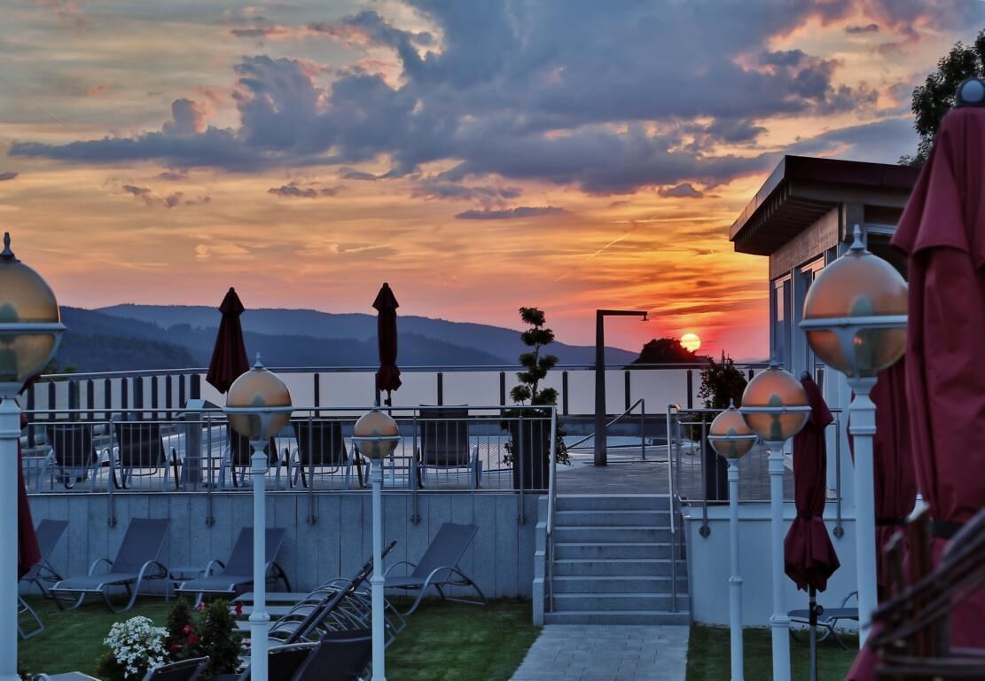 Une terrasse avec des sièges extérieurs, un escalier et une vue sur le coucher de soleil.