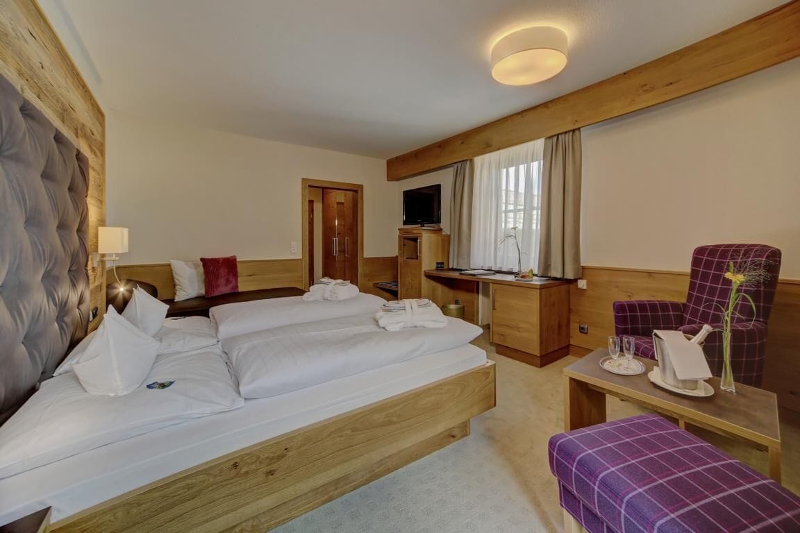 A hotel room with a large bed, a desk, a chair, and a television.
