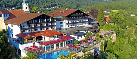 A hotel with multiple buildings, a swimming pool, and a mountain backdrop.