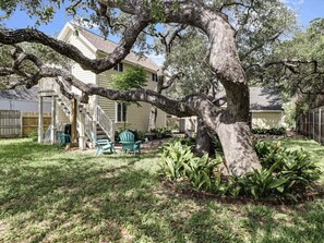 A house with a large tree in the yard, a covered porch, and a small shed.