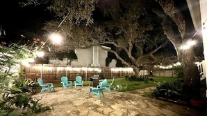 Un espace extérieur aménagé en terrasse, avec un sol en pierre, un barbecue et des chaises turquoise.
