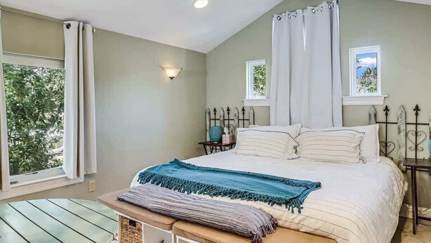 Une chambre à coucher comprenant un lit, un banc, une fenêtre et un luminaire fixé au mur.