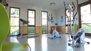 Une salle de sport équipée de matériel d’exercice, dotée de grandes fenêtres et comprenant une chaise verte.