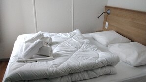 Un lit bien fait, avec du linge de lit blanc et des serviettes pliées.
