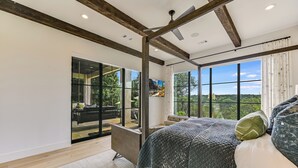 Ein Schlafzimmer mit einem großen Bett, Blick ins Freie und einem modernen Design mit freiliegenden Balken.