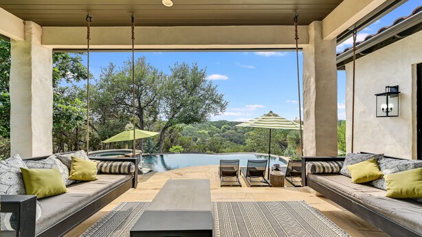 Ein überdachter Sitzbereich mit Blick auf Pool und Bäume.