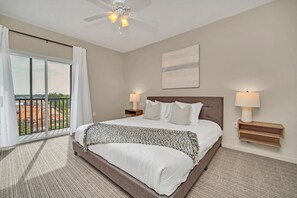 A hotel room with a large bed, two bedside lamps, a ceiling fan, and a view through a sliding glass door. - Family-friendly Condo With Pool, Hot Tub & Sauna (Winter Garden)