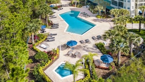 An aerial view of a resort with a large central pool, multiple lounge areas, and surrounding greenery. - Family-friendly Condo With Pool, Sauna & Hot Tub (Winter Garden)