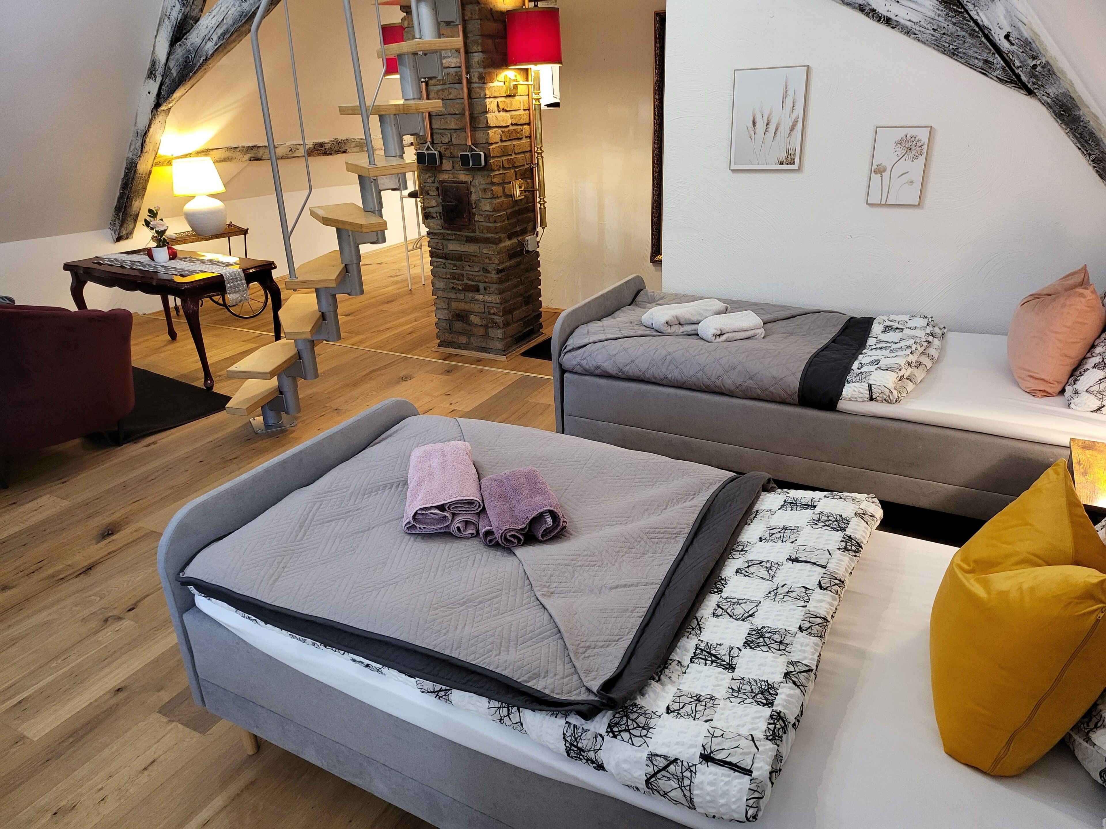 A cozy room with two beds, a staircase, and a desk.