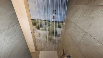 Ein modernes Badezimmer mit Duschkabine, freistehender Wasserhahn und Blick auf eine sandige Landschaft.