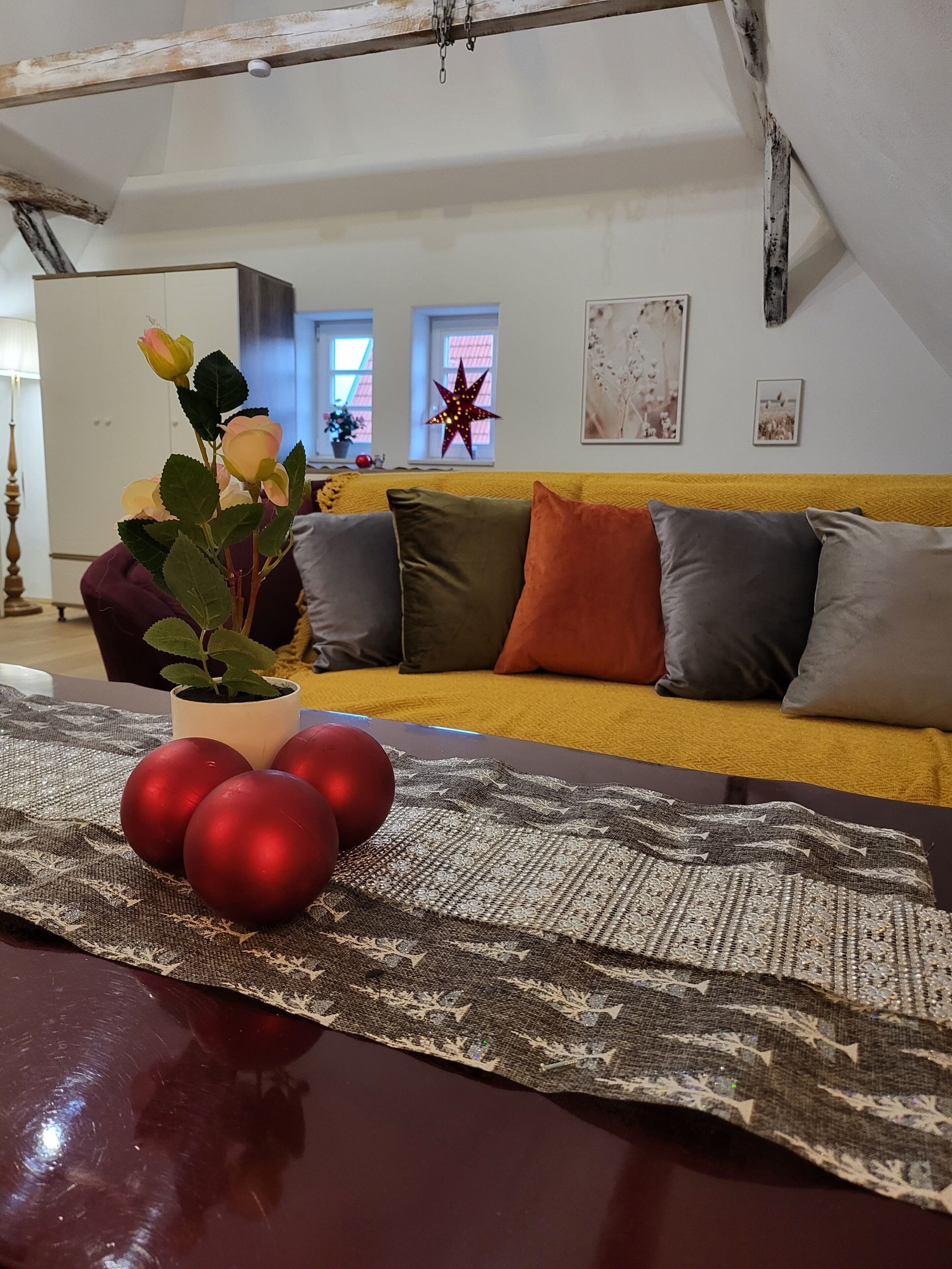En stue med sofa, puder, en stjernepyntning og en potteplante med blomster.