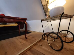 A wooden floor, a wooden table, a lamp, and a metal cart with a plate on top.