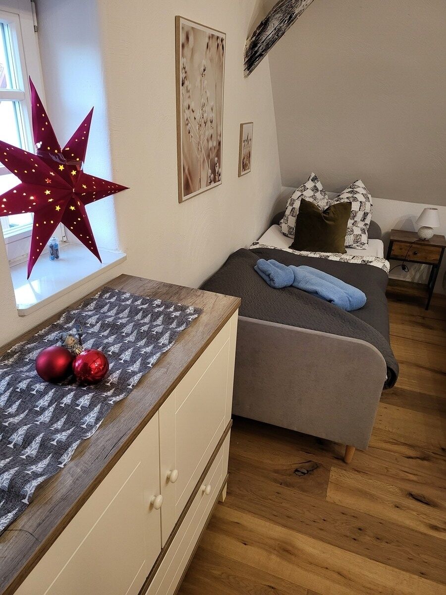 A bedroom with a bed, a dresser, a window, and a star decoration.