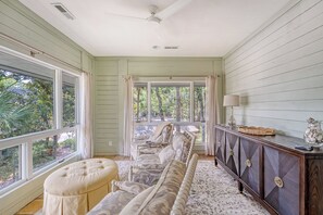 A spacious room with a large window, a sofa, a cabinet, and a ceiling fan.