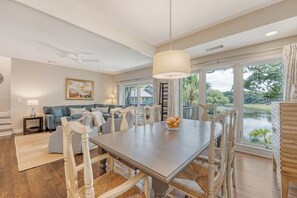A dining area with a large table, chairs, and a hanging light fixture.