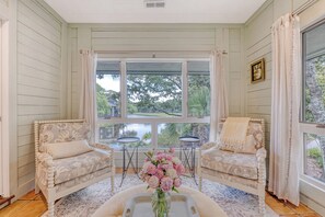 A cozy room with two upholstered chairs, a small table, and a vase of flowers.