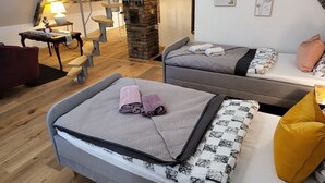 A cozy room with two beds, a staircase, and a desk.
