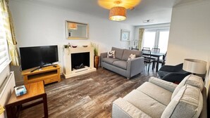 A living room with a fireplace, a television, a sofa, and a dining area.
