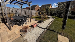 A patio with a wooden pergola, a table, and chairs.