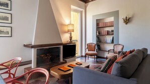Een gezellige woonkamer met een open haard, een boekenkast en comfortabele zitplaatsen.