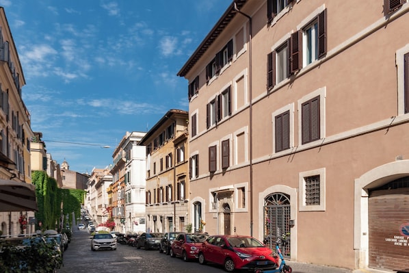 A narrow cobblestone street lined with parked cars and historic buildings with arched doorways and shutters. - PRESTIGIOUS 3-BEDROOM APARTMENT (Roma)