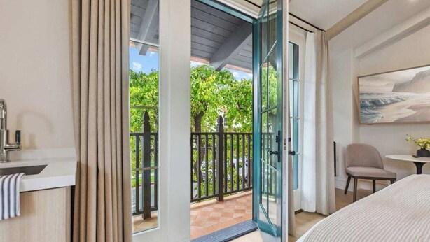 A modern bedroom with a large bed, a bedside table, a chair, and a painting on the wall. - Casa Riviera 28 - Boutique Suites (Santa Barbara)