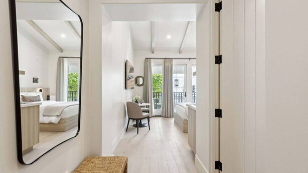 A modern hotel room with a large mirror, a bench, a desk, and a view of the balcony. - Casa Riviera 29 - Boutique Suites (Santa Barbara)