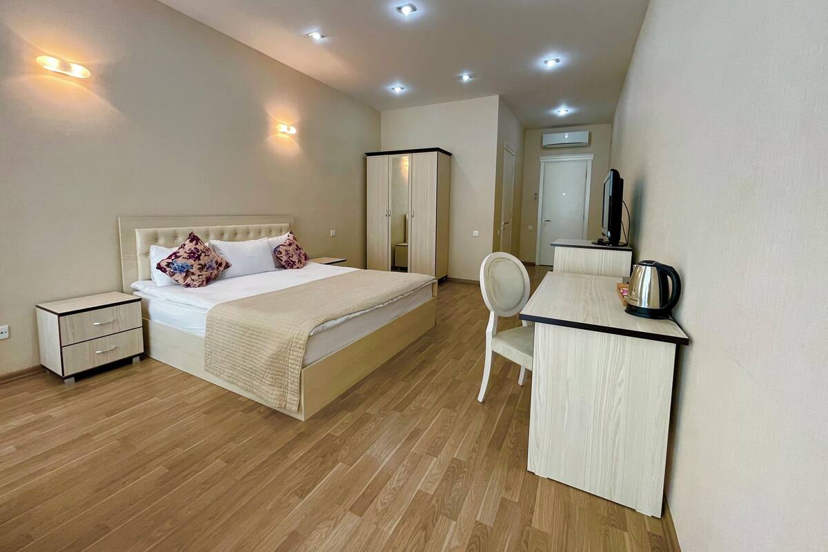 A modern bedroom with a bed, bedside table, and a desk with a chair.