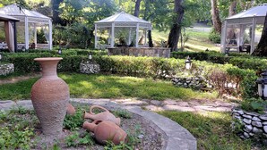 A garden with a large terracotta vase, stone lanterns, and two white gazebos with intricate lattice designs. - Chukhur Gabala Museum Hotel (Gabala)