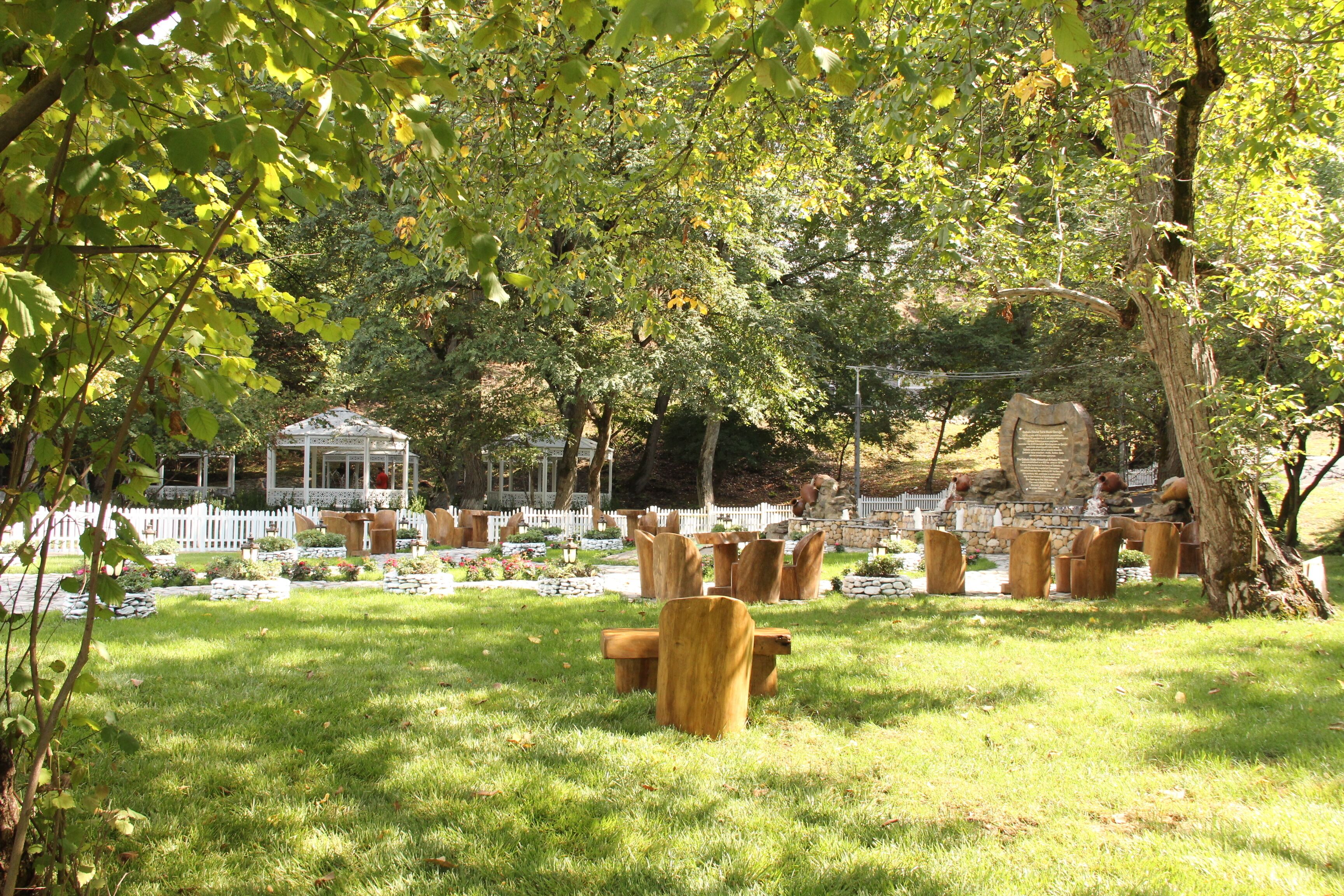 A garden with wooden benches, a gazebo, and a stone wall.