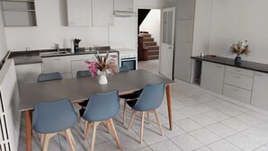 Una cucina moderna con mobili bianchi, un'isola centrale con sedie e un tavolo da pranzo.