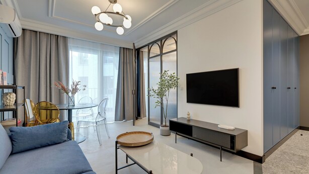 A modern living room with a sofa, a coffee table, a TV, and a dining area with chairs and a table. - Żurawie IKONY 1 by Grand Apartments (Gdansk)