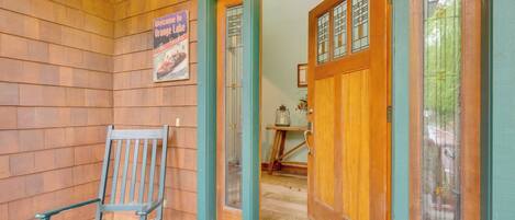 A wooden exterior with a wooden chair, a door with glass panels, and a welcome sign.