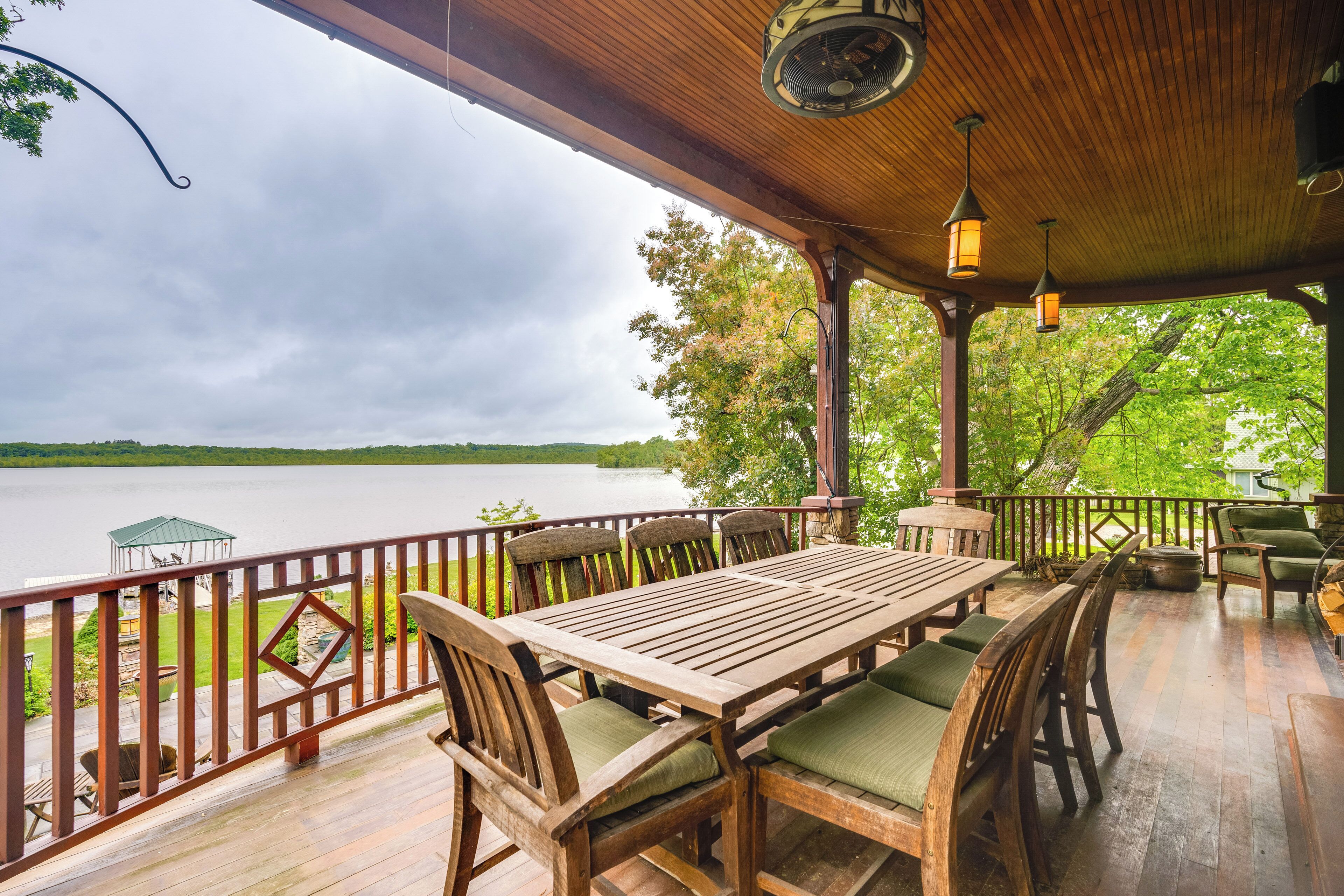 Terraza de madera con mesa y sillas, con vista a un lago.