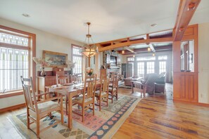 A spacious dining area with wooden furniture, a chandelier, and large windows. - Luxe Family Home on Orange Lake w/ Private Dock! (Newburgh)