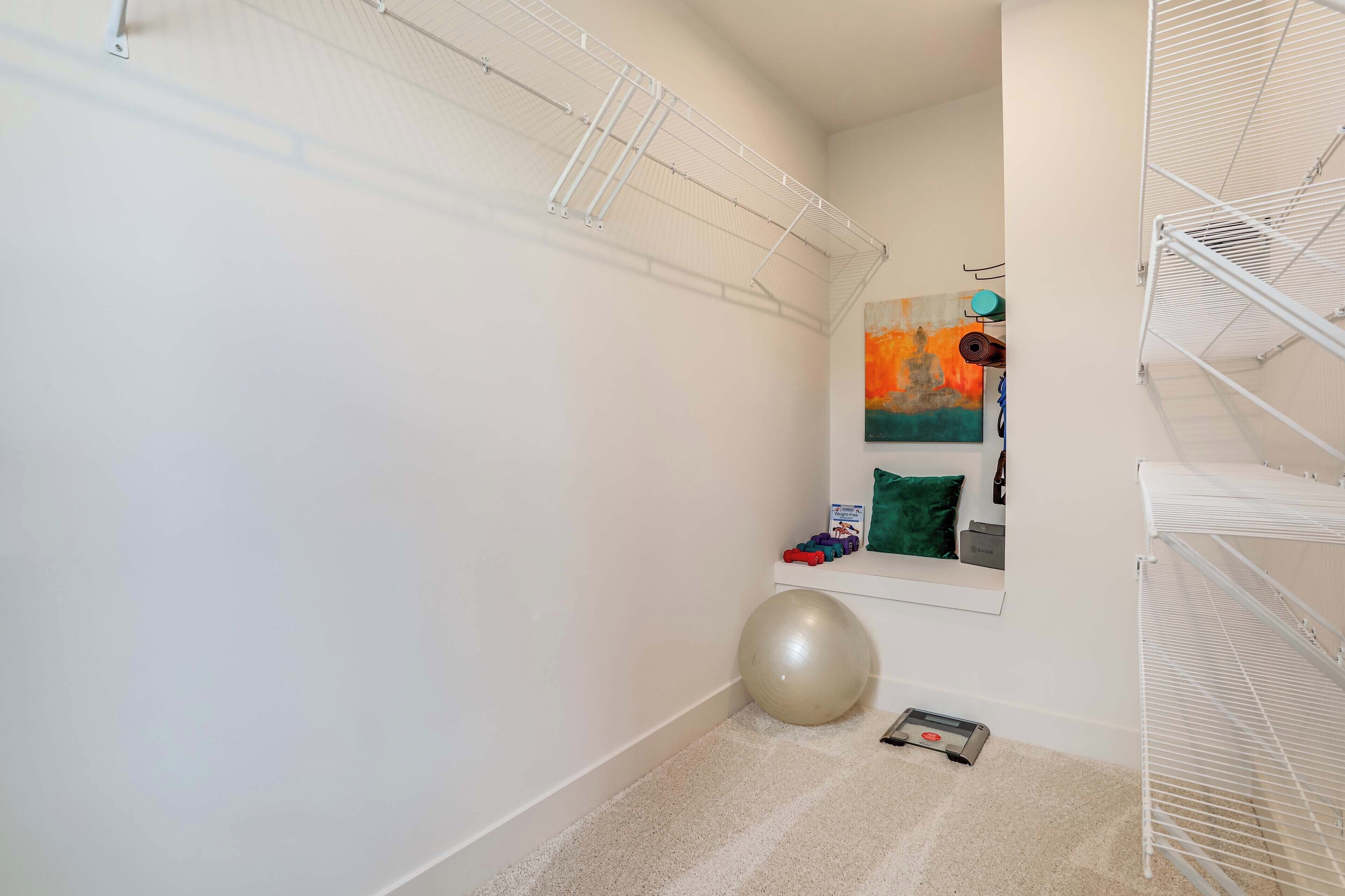 Une pièce de taille modeste avec un plafond blanc, un grand ballon d’exercice et un tapis de course.