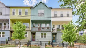 A row of three-story townhouses with front porches and a black metal fence in front.