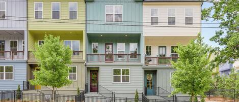Una hilera de casas urbanas de tres pisos con porches delanteros y una cerca de metal negro.